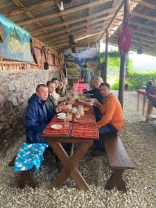 a group of people sitting around a wooden table at Casa de campo Sarawasi Hostel-Restaurant in Mollepata