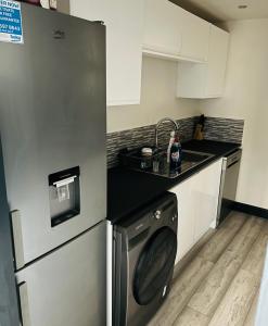 a kitchen with a refrigerator and a washing machine at Green Lantern, Private En-suite Double Bedroom in Aveley