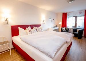 a bedroom with a large white bed with a red headboard at Hotel Haus Nachtigall - B&B in Uedem