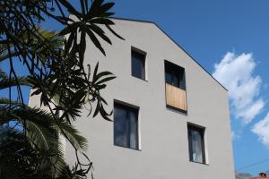a white building with black windows and a palm tree at Picobello Lago in Mandello del Lario