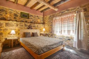 1 dormitorio con 1 cama en una habitación con paredes de piedra en Hani Kastania - Chania retreat for families and groups for holidays and workshops en Sémbronas