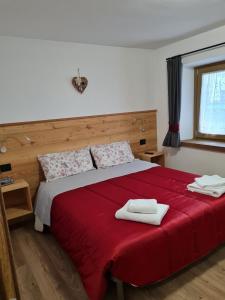 una camera da letto con un letto rosso con due asciugamani di Casa Tiziano e Nila a Santo Stefano di Cadore