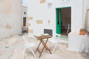 a table and chairs on a patio with a green door at Dimora Clessidra in Patù