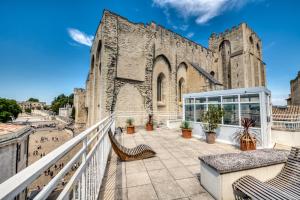 un gran edificio de piedra con bancos delante en Mercure Avignon Centre Palais des Papes, en Aviñón