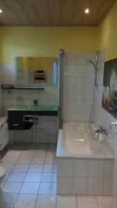 y baño con ducha, bañera y lavamanos. en Apartment Halmis FeWo WR, en Wernigerode