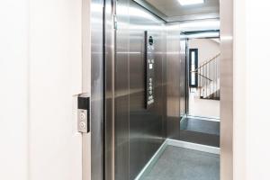 un ascenseur en acier inoxydable dans un couloir avec un escalier dans l'établissement Simba Klínovec by Mountain ways, à Loučná pod Klínovcem