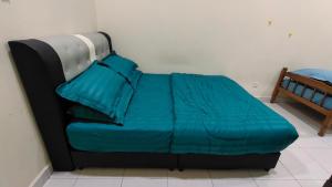 Sentosa2Stay Gong Badak Kuala Terengganu في كامبونغ غونغ بدك: سرير مع لحاف ووسائد زرقاء عليه