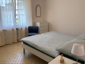 a bedroom with a bed and a blue chair at Appartamento con giardino al Melograno in Locarno