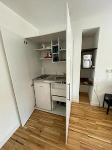 a small kitchen with white cabinets and a wooden floor at Bungalow mit Terrasse in Regensburg