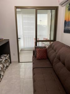 ein Wohnzimmer mit einem braunen Sofa und einem Tisch in der Unterkunft Apartamento em condominio praia clube in Caraguatatuba + 32 Fotos