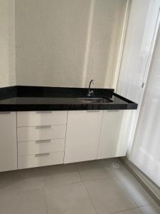 eine Küche mit schwarzer Arbeitsplatte und Spüle in der Unterkunft Apartamento em condominio praia clube in Caraguatatuba