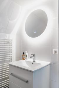 a white bathroom with a sink and a mirror at Tiny Attic on the Herengracht, Private Room in Amsterdam