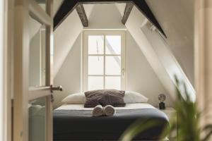 a bed with two slippers on it in a room with a window at Tiny Attic on the Herengracht, Private Room in Amsterdam