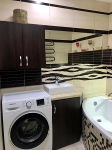 a bathroom with a washing machine and a sink at Apartament SŁONECZNY Mrzeżyno in Mrzeżyno