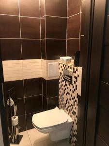 a bathroom with a toilet and black and white tiles at Apartament SŁONECZNY Mrzeżyno in Mrzeżyno