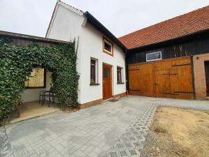 una casa bianca con una porta in legno e un patio di Ferienhaus Rhöner Auszeit a Kaltenwestheim