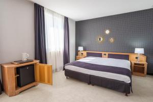 una camera con un letto e una televisione di Hôtel Le Picardy a Saint-Quentin