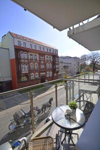 a balcony with a table and a dog on the street at Apartamenty Bryza - Kwartał Róży Wiatrów in Świnoujście