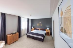 um quarto de hotel com uma cama e um sofá em Hôtel Le Picardy em Saint-Quentin