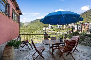 a table and chairs with a blue umbrella on a patio at Appartamento Aurora in Corniglia