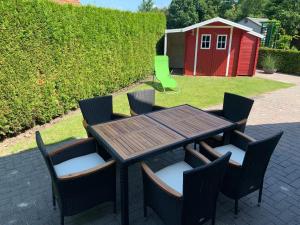 uma mesa de madeira com cadeiras e um barracão vermelho em Neuhaus Deichperle em Krummhörn