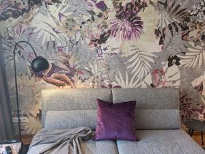リンダウにあるAlte Konditoreiの花の壁の前に紫色の枕が付いたソファ