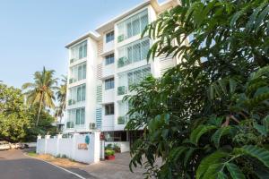a tall white building with green shuttered windows at Arotel Rooms & Suites in Calangute