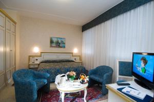 a hotel room with a bed and chairs and a television at Hotel Internazionale Terme in Abano Terme