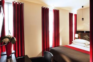 a bedroom with red drapes and a bed with a chair at Hôtel Caron le Marais in Paris