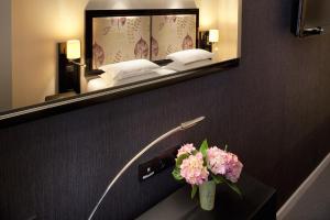 a hotel room with a mirror and a table with flowers at Hôtel Caron le Marais in Paris +14 photos