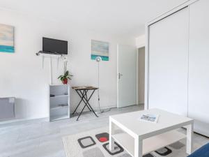 Una sala de estar blanca con una mesa y un televisor. en Apartment Les Hélianthes-1 by Interhome, en Lacanau-Océan