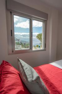 a bedroom with a red bed and a window at Luxurious apartment with large terrace and sea views in Tabaiba