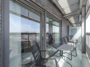 uma varanda com mesas, cadeiras e janelas de vidro em Apartment Railway to the Beach by Interhome em Blankenberge