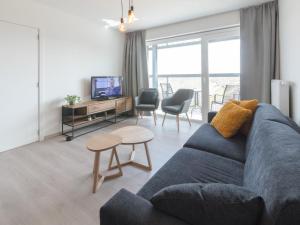 a living room with a blue couch and a tv at Apartment Railway to the Beach with balcony by Interhome in Blankenberge