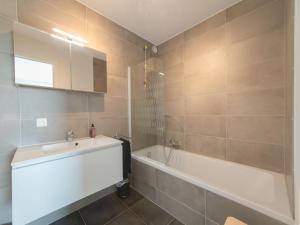 a bathroom with a tub and a sink and a bath tubermottermott at Apartment Railway to the Beach with balcony by Interhome in Blankenberge
