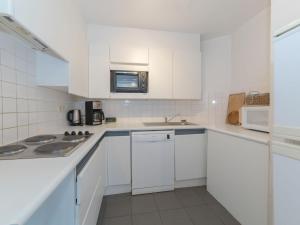 een witte keuken met witte kasten en een magnetron bij Apartment Jong & Blij 2 by Interhome in De Haan