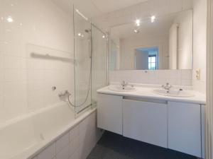 een witte badkamer met 2 wastafels en een douche bij Apartment Jong & Blij 2 by Interhome in De Haan
