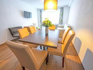 a dining room with a wooden table and yellow chairs at Apartment Inntalerhof-1 by Interhome in Tösens
