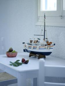 ein Spielzeugboot auf einem Tisch neben einem Apfel in der Unterkunft Ninetta's Studios in Poros