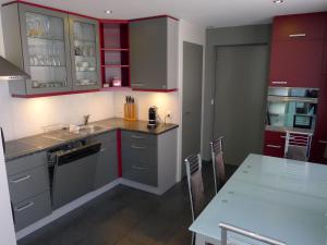 Apartment Schlieregg by Interhome في Hirzel: مطبخ مع دواليب حمراء ورمادية وطاولة
