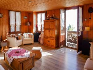 uma sala de estar com um sofá, uma mesa e janelas em Chalet Chalet Tsi-No by Interhome em Gryon