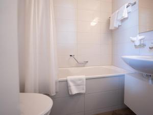 ein weißes Badezimmer mit einer Badewanne und einem Waschbecken in der Unterkunft Apartment Chesa Corvatsch 211 - Champfer by Interhome in Champfer