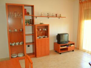 ein Wohnzimmer mit einem TV und einem Bücherregal aus Holz in der Unterkunft Apartment Apartamentos Golden Beach by Interhome in Sant Carles de la Ràpita