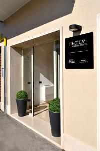 a building with two potted plants in front of a window at BB Hotels Aparthotel Bicocca in Milan