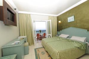 a bedroom with a bed and a television and a balcony at Hotel Royal Beach in Sousse