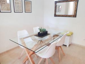 a glass dining room table with white chairs and a mirror at Apartment Vila del Far by Interhome in Sant Carles de la Ràpita