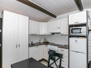 a kitchen with white cabinets and a black table and a chair at Holiday Home A-sauna by Interhome in Pori