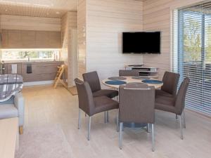 sala de estar con mesa, sillas y TV en Holiday Home Holy lake rantasauna by Interhome en Niskala