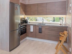 uma cozinha com armários de madeira e um frigorífico de aço inoxidável em Holiday Home Holy lake rantasauna by Interhome em Niskala