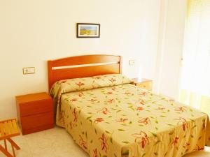 1 dormitorio con 1 cama con edredón amarillo en Apartment Aldea Park by Interhome, en Sant Carles de la Ràpita